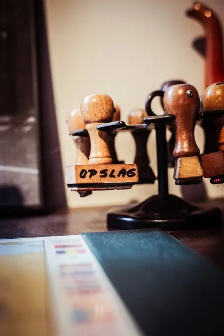Oude houten douanestempels op een draaimolen, één met het opschrift OPSLAG